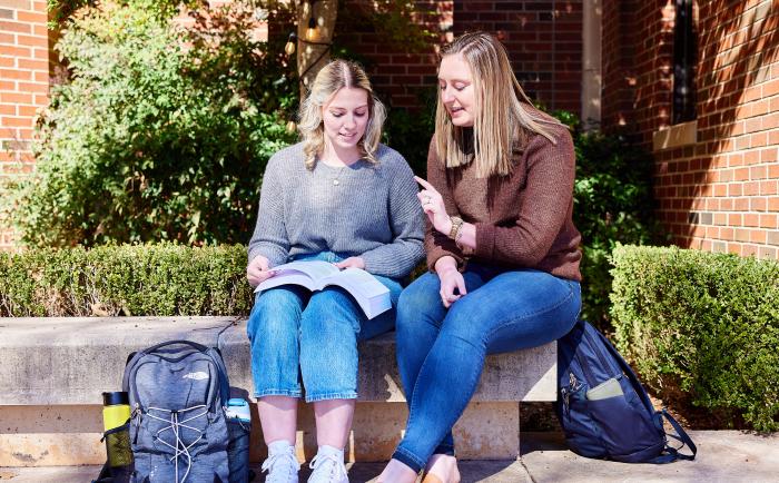 Students talking outside on a bench